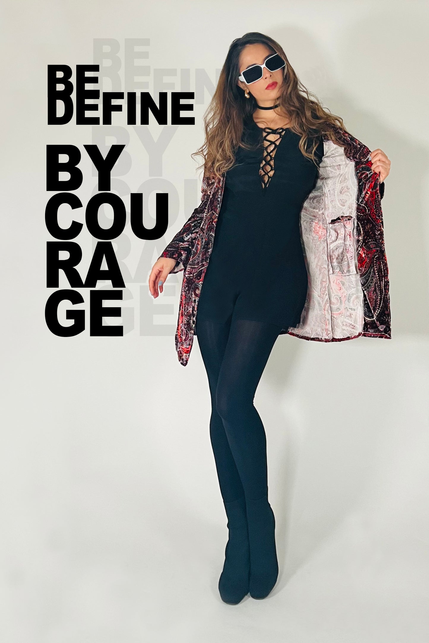 Person wearing a black outfit with a patterned jacket against a white background with text.