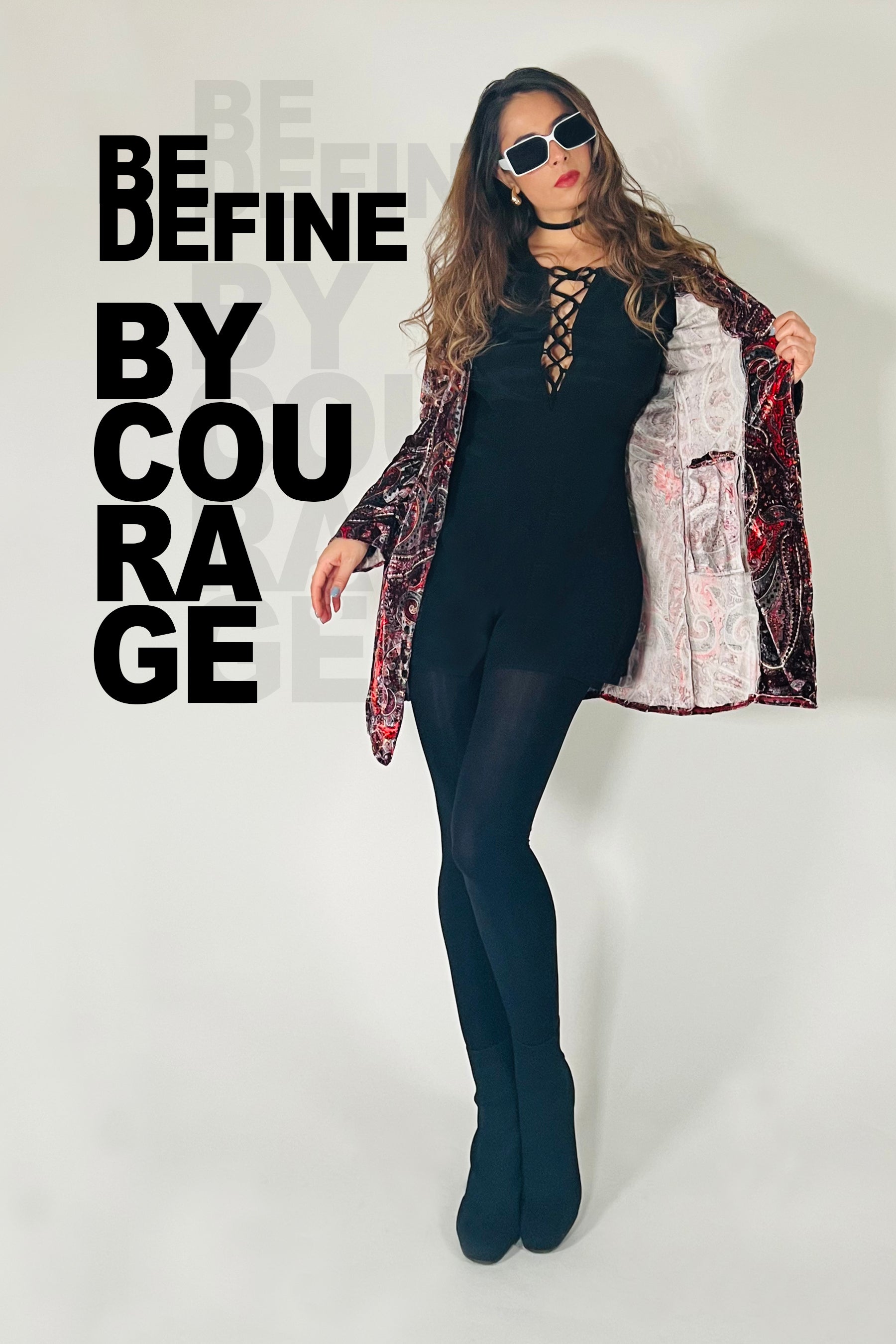 Person wearing a black outfit with a patterned jacket against a white background with text.