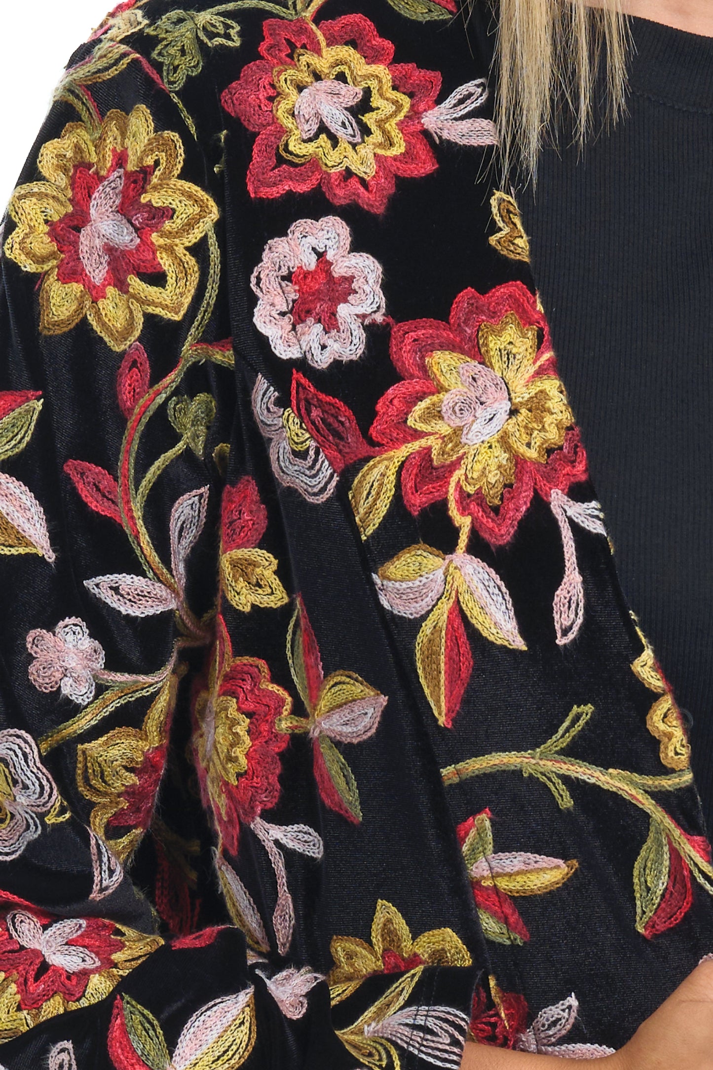 Detail of velvet cardigan with black red yellow embroidery over a black-tshirt