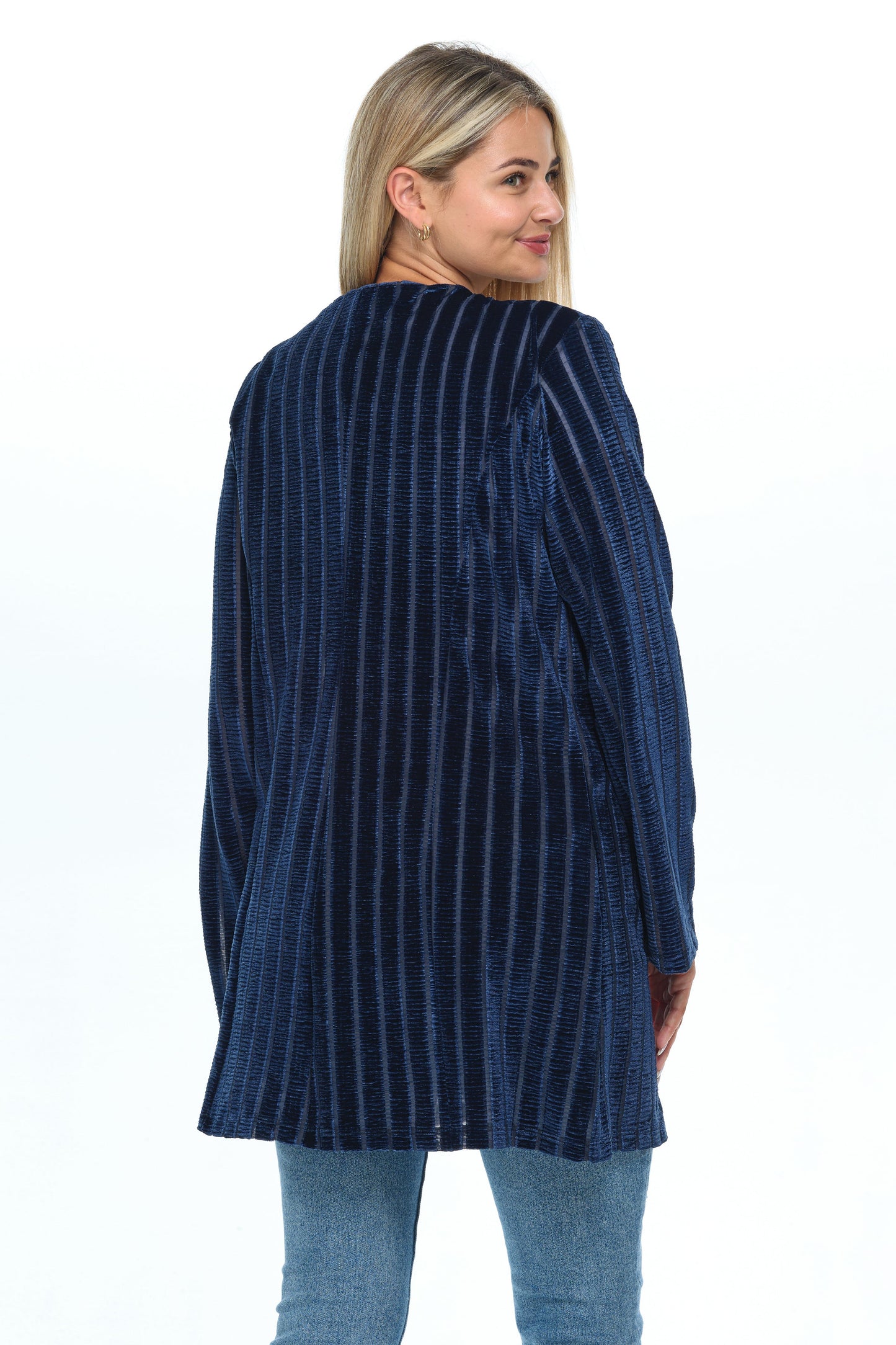 Back view head-to-knees body of blond-mid-20s model standing on white background and looking to the right wearing a velvet cardigan with long sleeves and two pockets colored navy blue stripped and jeans-tshirt outfit