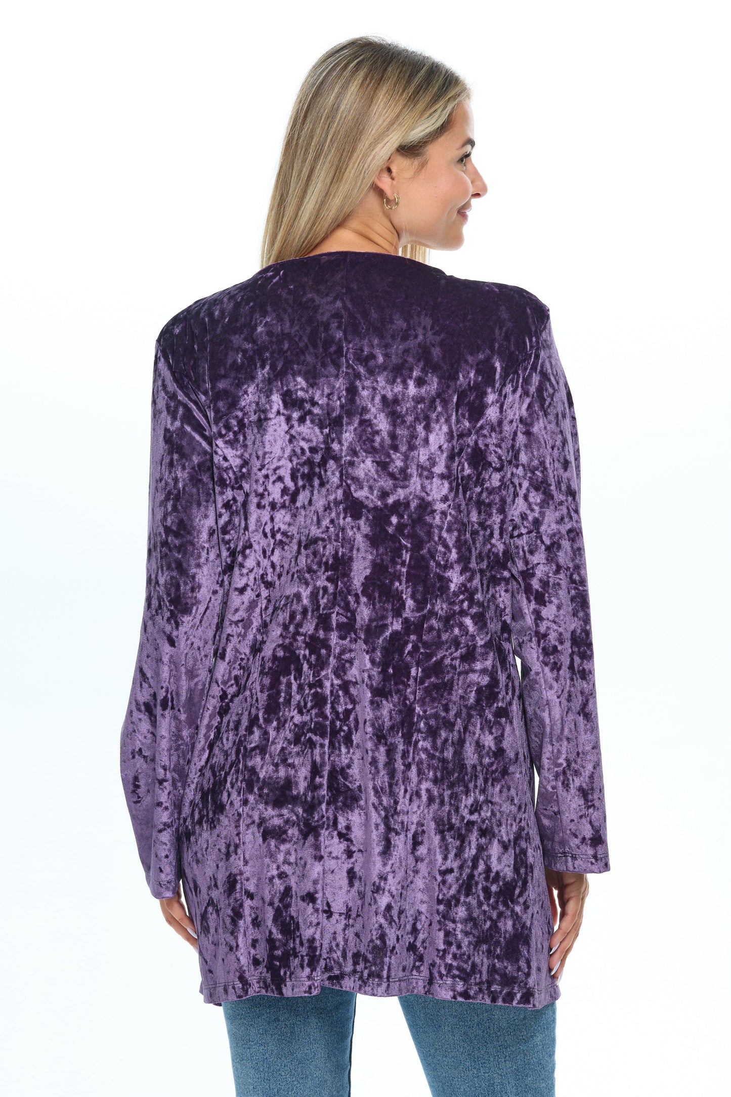 Back view head-to-knees body of blond-mid-20s model standing on white background and looking to the right wearing a velvet cardigan with long sleeves and two pockets colored purple shine eggplant and jeans-tshirt outfit